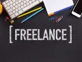 Biurko z klawiaturą, telefonem i napisem "FREELANCE". To styl pracy, gdzie pracujesz dla różnych klientów, sam ustalając godziny.