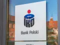 Logo PKO Bank Polski na drzwiach. W tle odbicie kamienicy.
