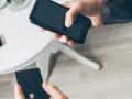 Dłoń trzyma smartfon, druga dłoń czarną kartę płatniczą. Szybkie płatności zbliżeniowe, jak w PKO BP, to wygoda.
