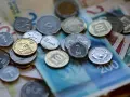 Stos monet i banknotów, w tym szekla, tworzy bogactwo na stole.