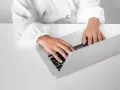 Osoba w białej koszuli pisze na laptopie, przygotowując zaświadczenie o niezaleganiu ZUS.