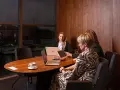 Trzy kobiety omawiają strategię w nowoczesnym biurze. Dyskretne spotkanie, które może dotyczyć usług private banking.