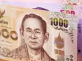 Tajskie baty: banknot 1000 bahtów z wizerunkiem króla i banknot 500 bahtów w tle.