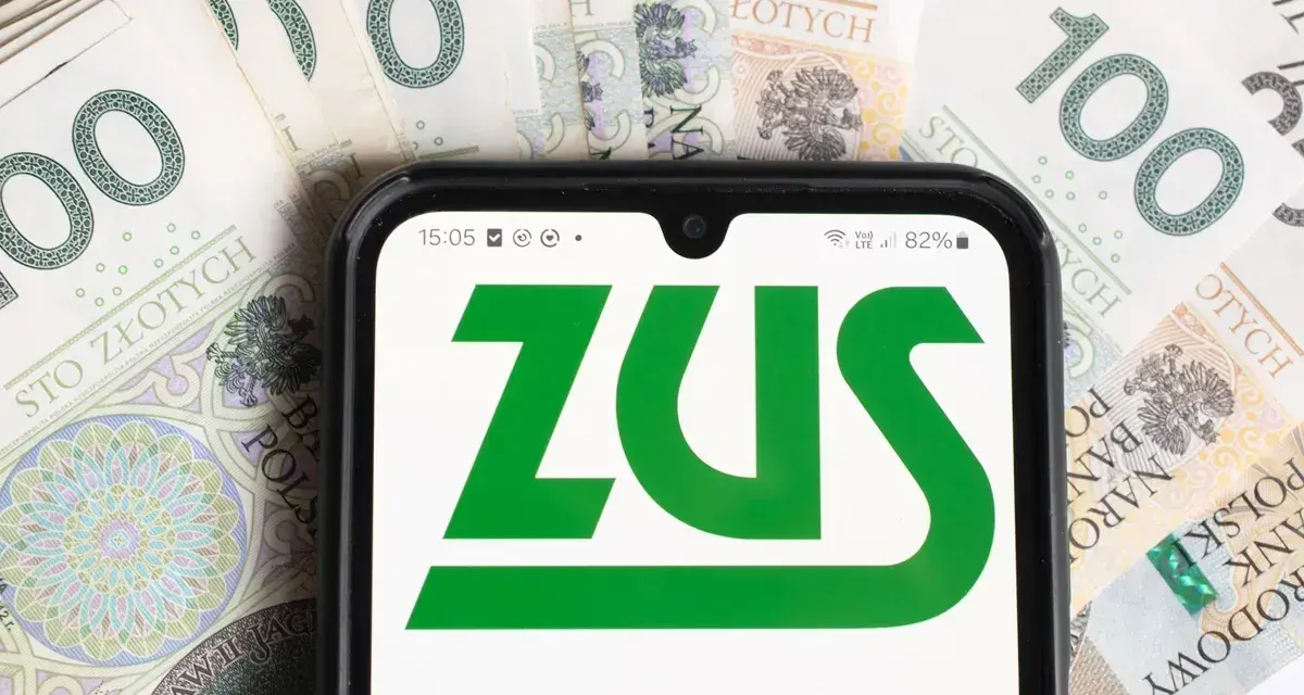 Smartfon z logo ZUS na tle polskich banknotów 100 zł.