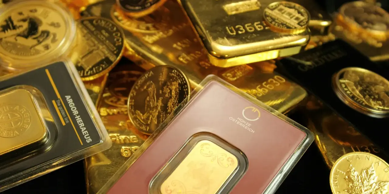 Złote sztabki i monety, w tym gram złota w opakowaniu z napisem "The golden link".
