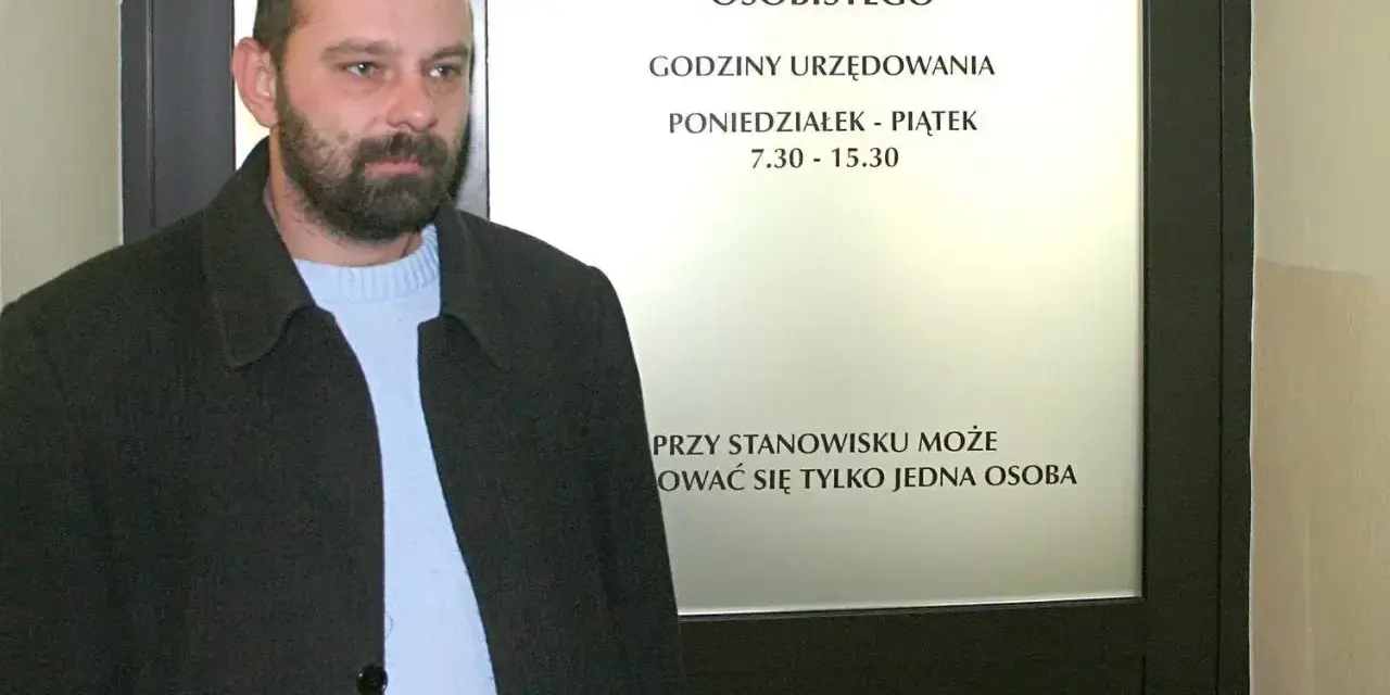 Mężczyzna z brodą przed urzędem, gdzie można złożyć wniosek o dowód. Sprawdź, ile kosztuje wyrobienie dowodu i godziny otwarcia.
