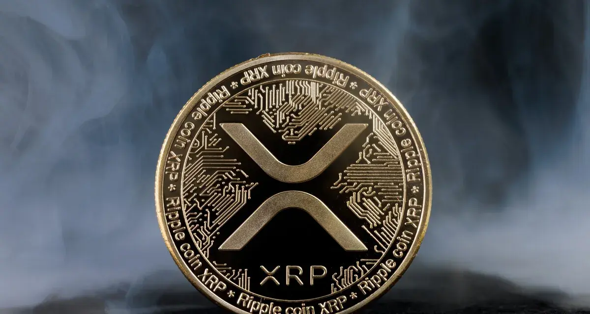 Złoty token kryptowaluty XRP, otoczony mgłą, symbolizuje przyszłość finansów.