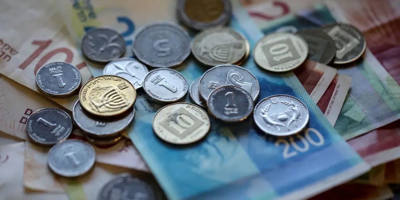 Stos monet i banknotów, w tym szekla, tworzy bogactwo na stole.