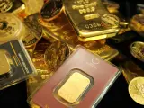Złote sztabki i monety, w tym gram złota w opakowaniu z napisem "The golden link".