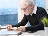 Starszy mężczyzna w okularach analizuje dokumenty, planując swoją ochronę przedemerytalną.
