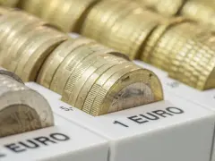 Złote monety euro, symbol włoskiej waluty, ułożone w przegródkach z oznaczeniami wartości.