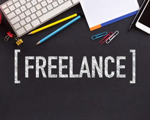 Biurko z klawiaturą, telefonem i napisem "FREELANCE". To styl pracy, gdzie pracujesz dla różnych klientów, sam ustalając godziny.