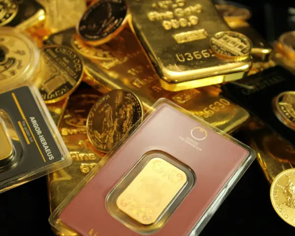 Złote sztabki i monety, w tym gram złota w opakowaniu z napisem "The golden link".