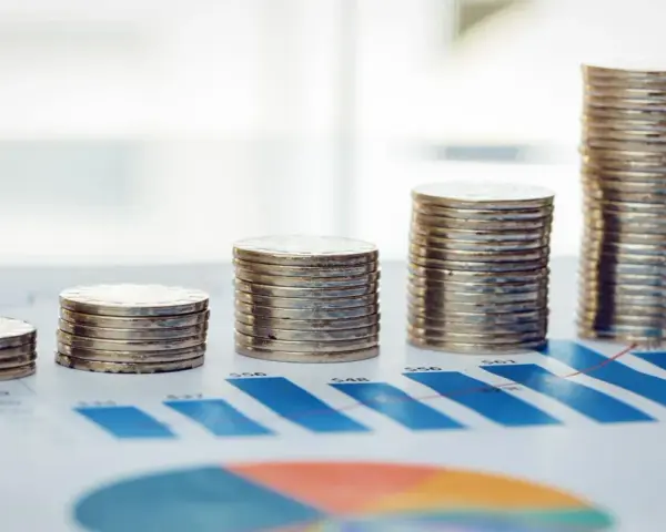 Rosnące stosy monet na wykresie symbolizują walkę z deficytem budżetowym i dążenie do stabilności finansowej.