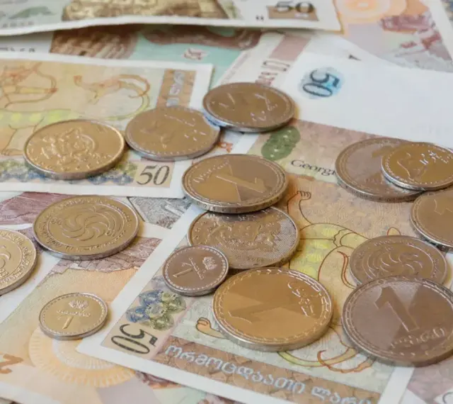 Monety i banknoty, w tym waluta Gruzji, lari, leżą rozrzucone na stole.