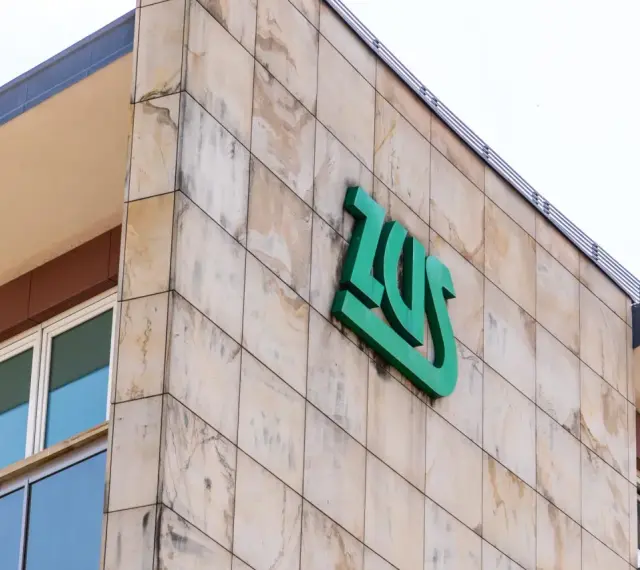 Budynek ZUS z zielonym logo. Zastanawiasz się, czy umowa zlecenie wlicza się do lat pracy do emerytury?