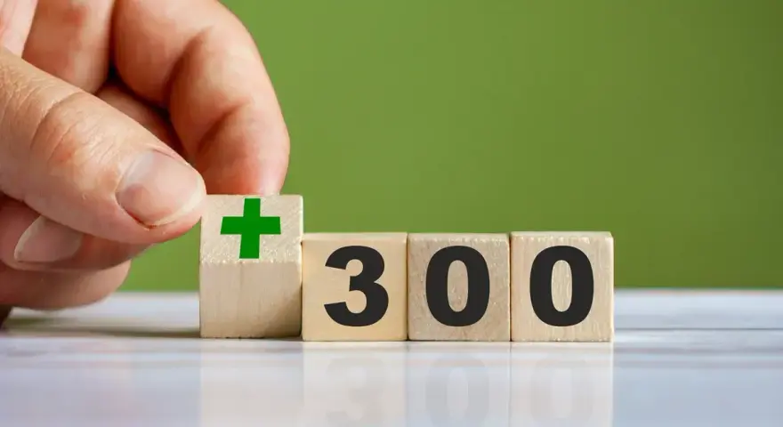 Dłoń układa kostkę z zielonym plusem obok kostek z napisem "300". To dobry start dla kogoś, kto chce zacząć coś nowego.