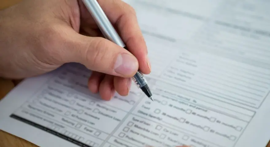 Dłoń z długopisem wypełnia formularz. Warto wiedzieć, jak znaleźć numer NIP, by poprawnie uzupełnić dokumenty.
