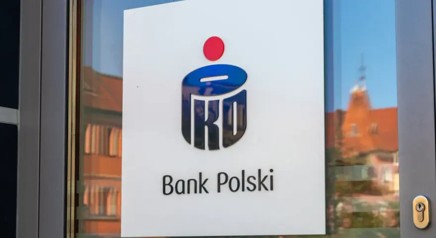 Logo PKO Bank Polski na drzwiach. W tle odbicie kamienicy.