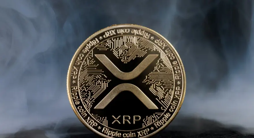 Złoty token kryptowaluty XRP, otoczony mgłą, symbolizuje przyszłość finansów.