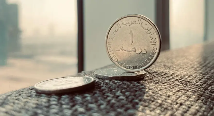 Monety z Zjednoczonych Emiratów Arabskich. Jedna z nich, z napisem "United Arab Emirates", stoi pionowo. To właśnie te monety symbolizują walutę AED, co to jest?