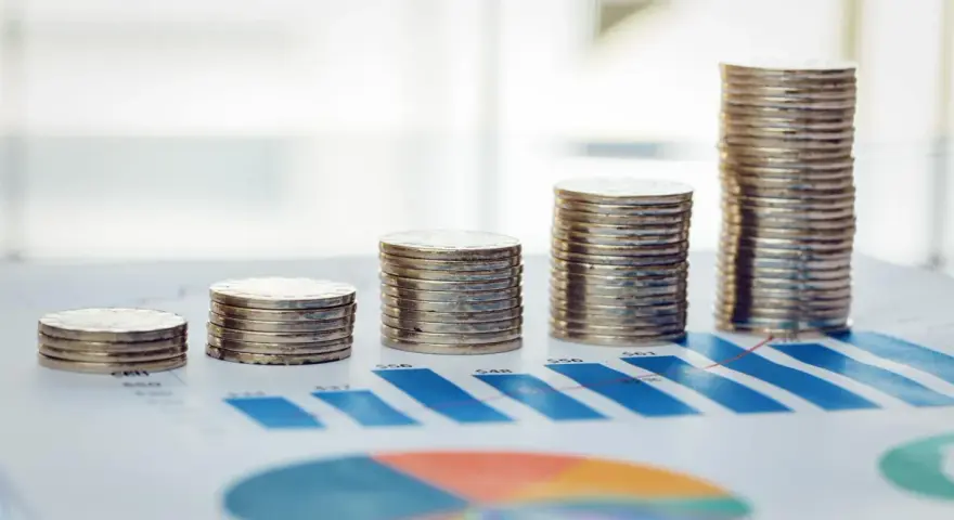 Rosnące stosy monet na wykresie symbolizują walkę z deficytem budżetowym i dążenie do stabilności finansowej.