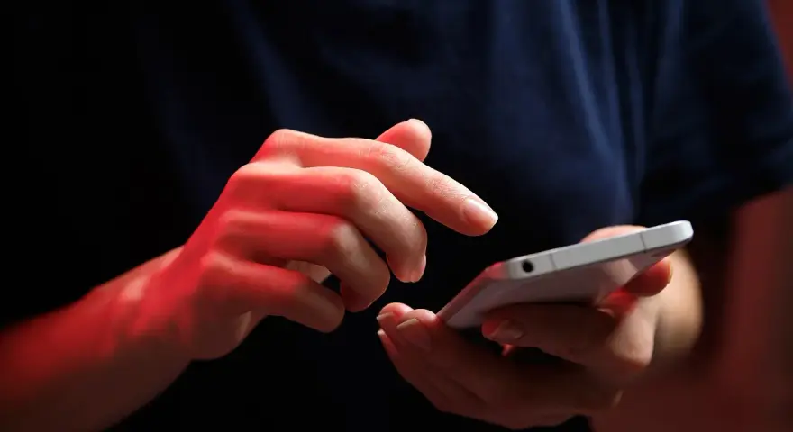 Dłonie z czerwonym podświetleniem obsługują smartfon, być może ustawiając **direct debit** na rachunki.