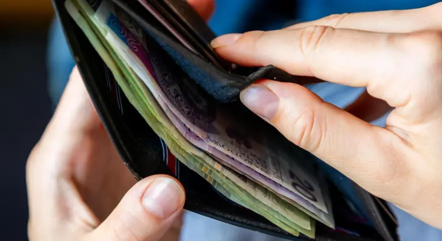 Dłonie przeglądają portfel z polskimi banknotami. Czy to początek drogi do dochodu gwarantowanego?