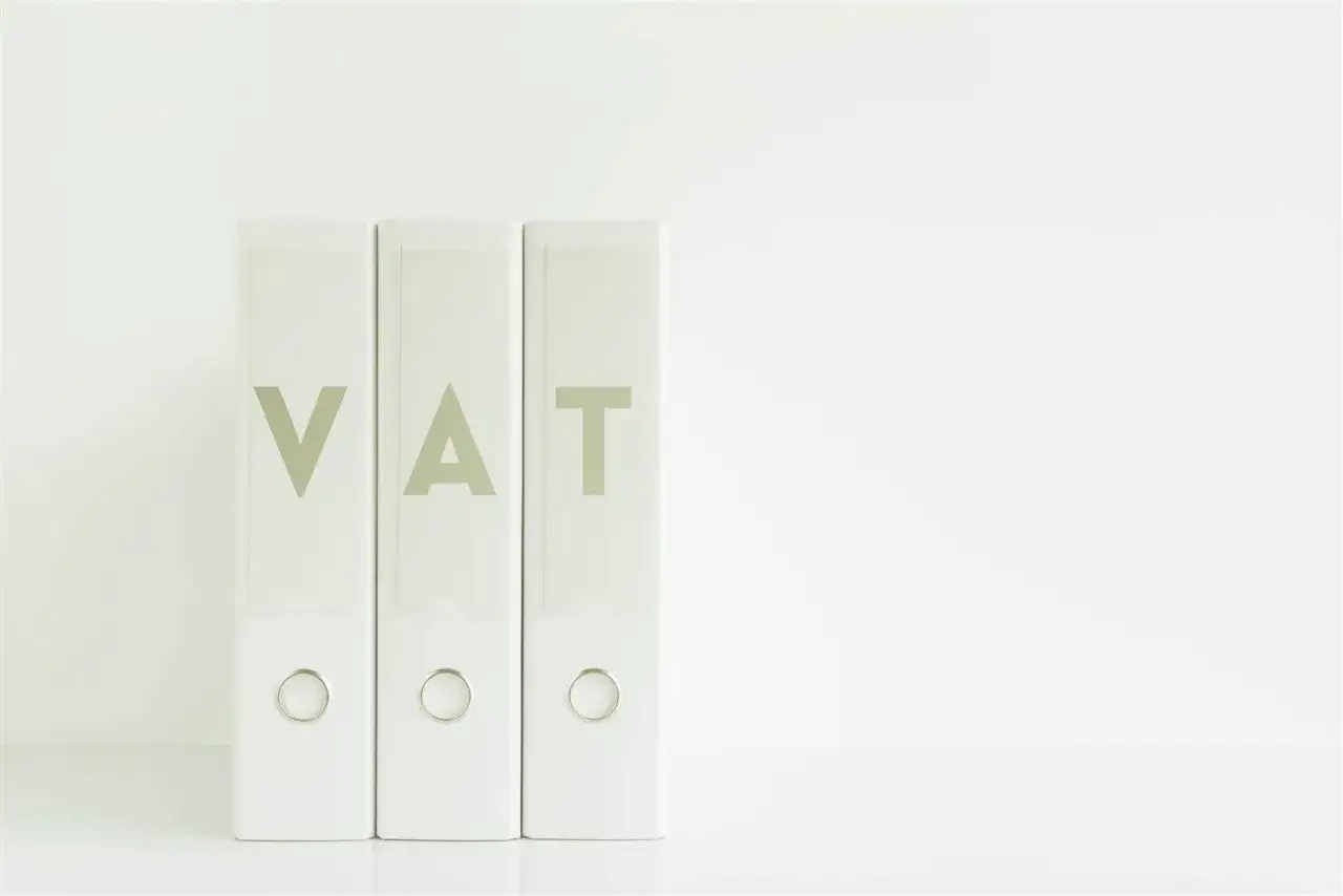 Trzy białe segregatory z napisem VAT. Dokumenty dotyczące podatku VAT uporządkowane na białej liście.