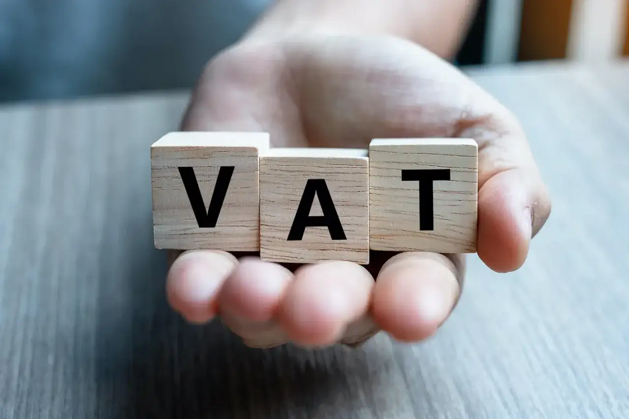 Drewniane klocki z napisem VAT w dłoni. Rozważasz biznes w Niemczech i zastanawiasz się nad kwestiami vat?