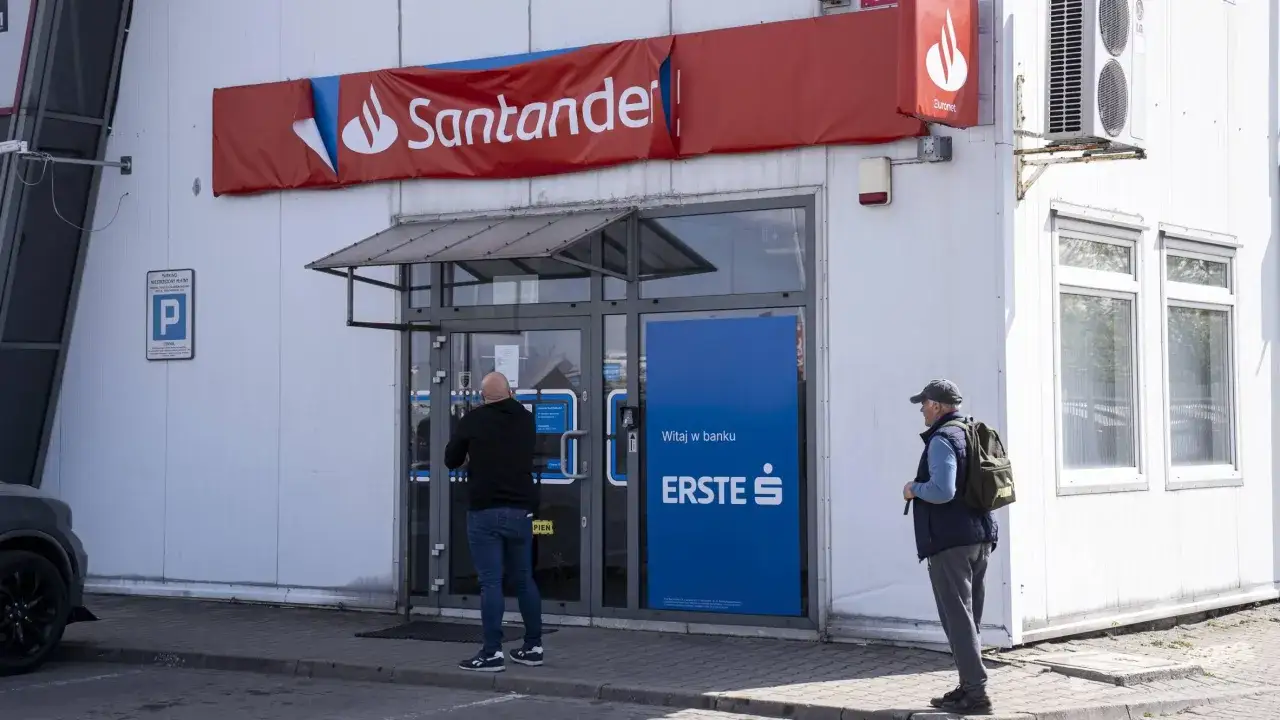 Przed wejściem do kantoru Santander stoi mężczyzna. Obok widoczny znak parkingu.