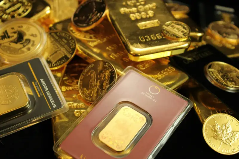 Złote sztabki i monety, w tym gram złota w opakowaniu z napisem "The golden link".